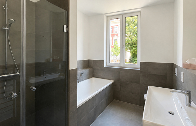 Helles Badezimmer mit Badewanne und Dusche.